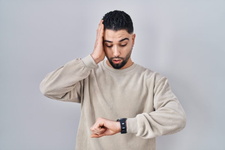 How Long Does Minoxidil Take To Work & See Visible Results? 3 Man touching his hair and looking at his watch