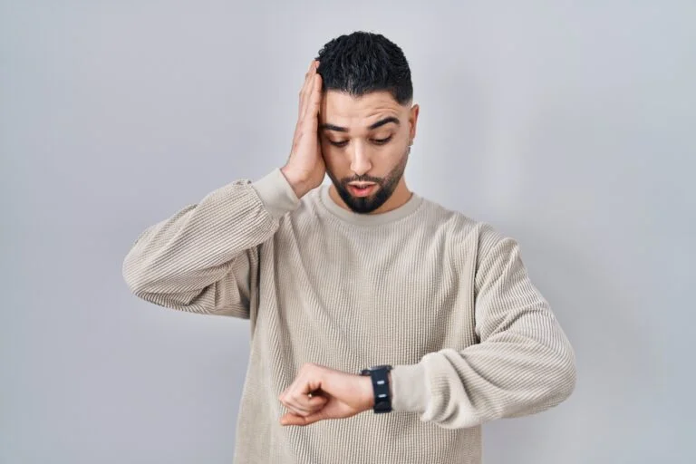 Hombre tocándose el pelo y mirando el reloj