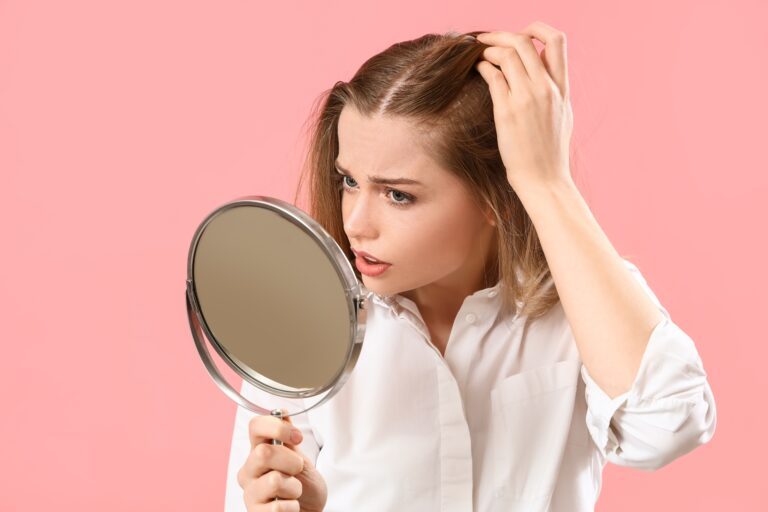 O Minoxidil de alta potência (10-15 %) é melhor para a queda de cabelo? 5 Mulher a inspecionar o seu cabelo com preocupação